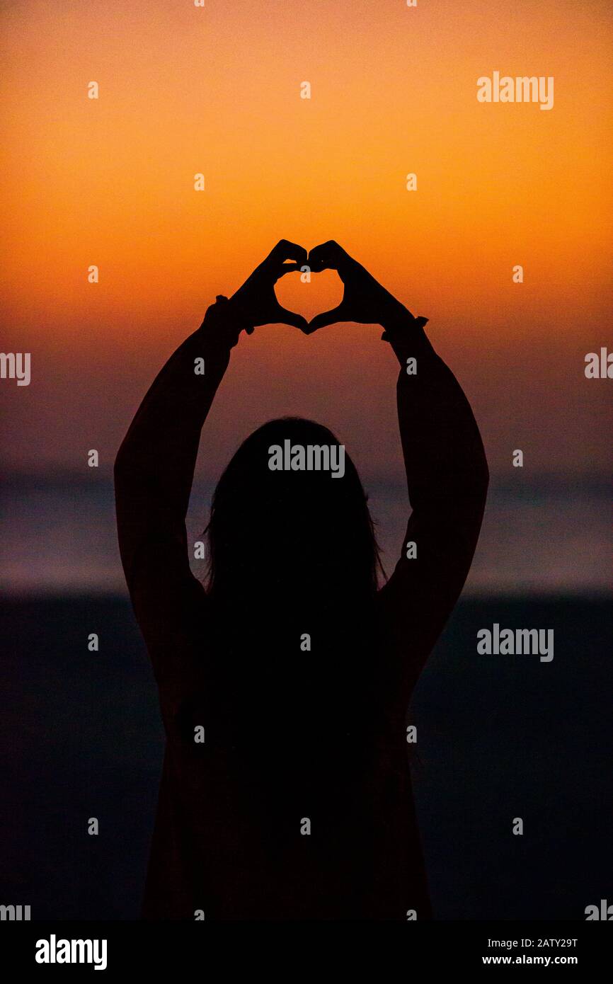 Silhouette of heart made by kids hand at sunset Stock Photo