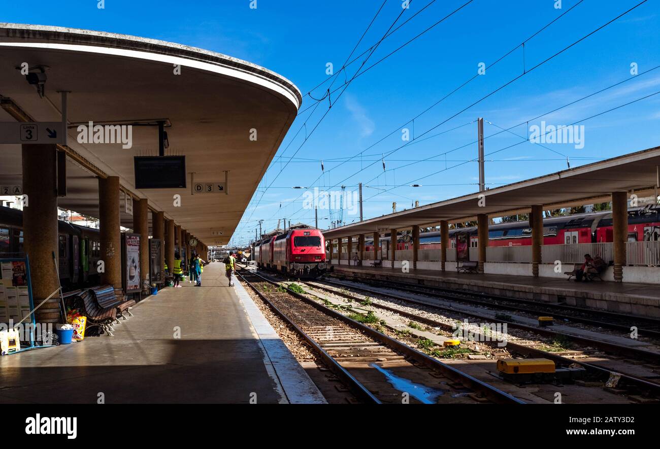 Janitors cleaning platform of Santa Apolonia train station with passenger train on the background. Stock Photo