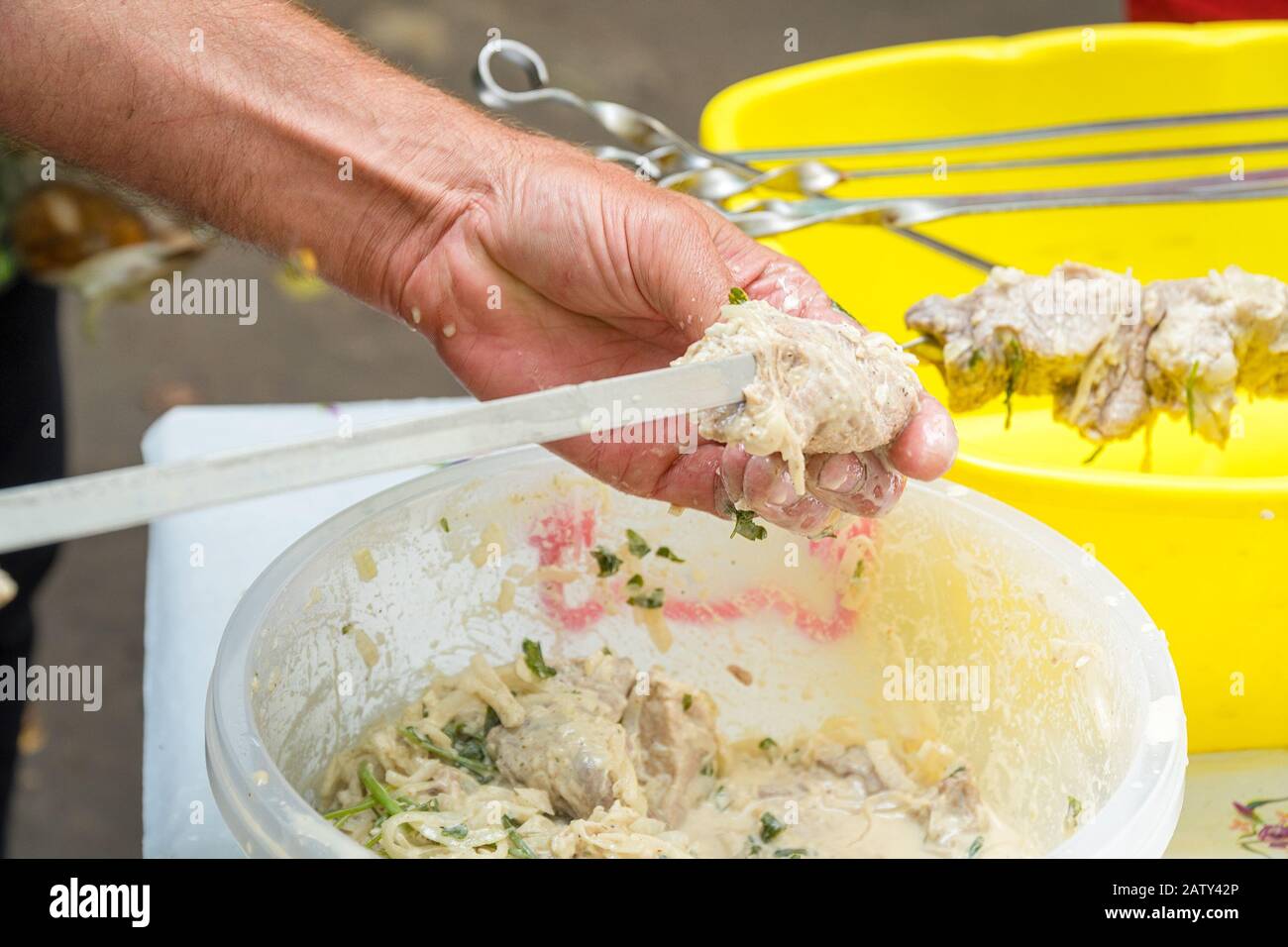 Man stringing marinated meat on a skewer for barbecue Stock Photo