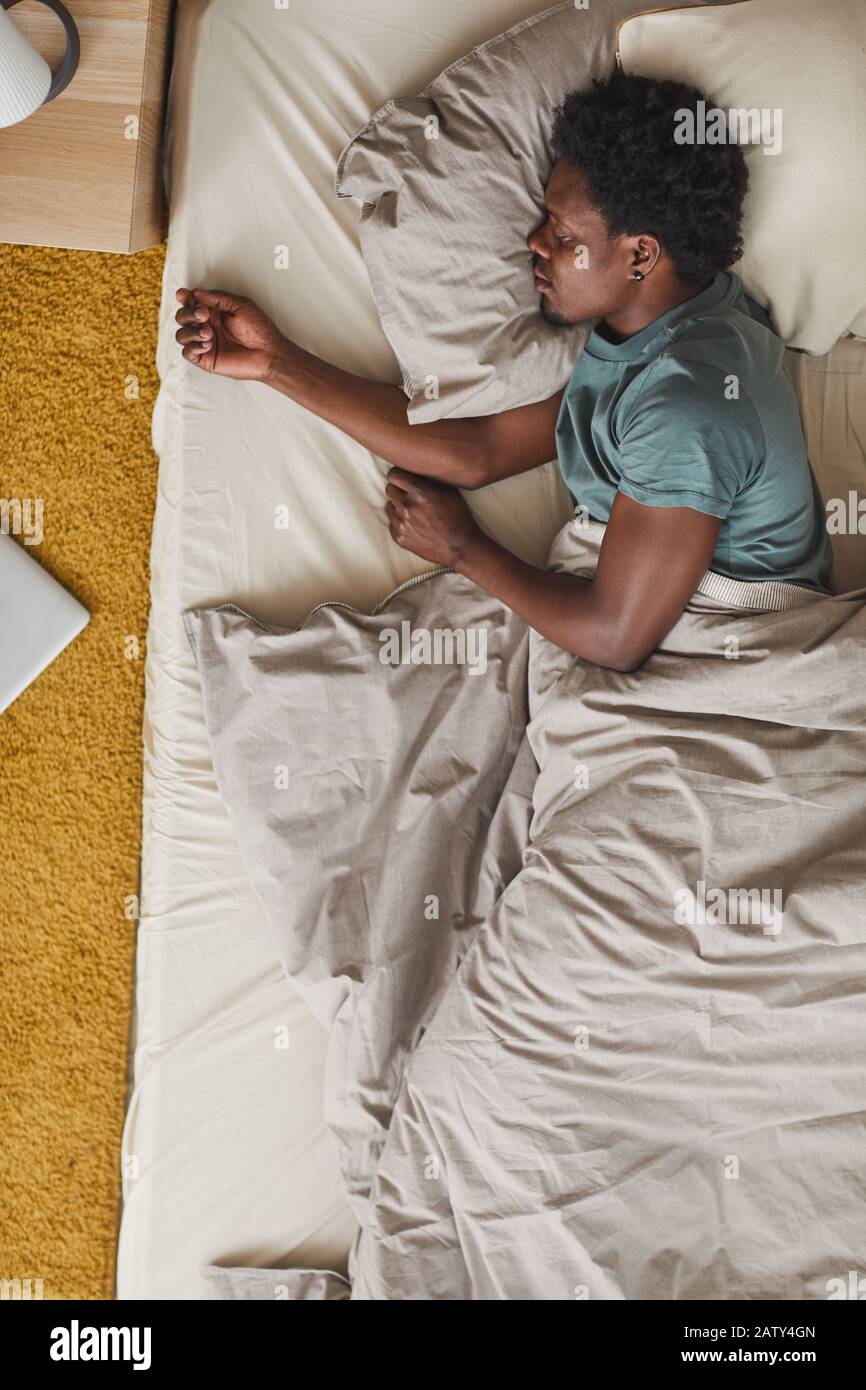 High angle view of African young man tired of hard day he sleeping in his  bed in the bedroom Stock Photo - Alamy