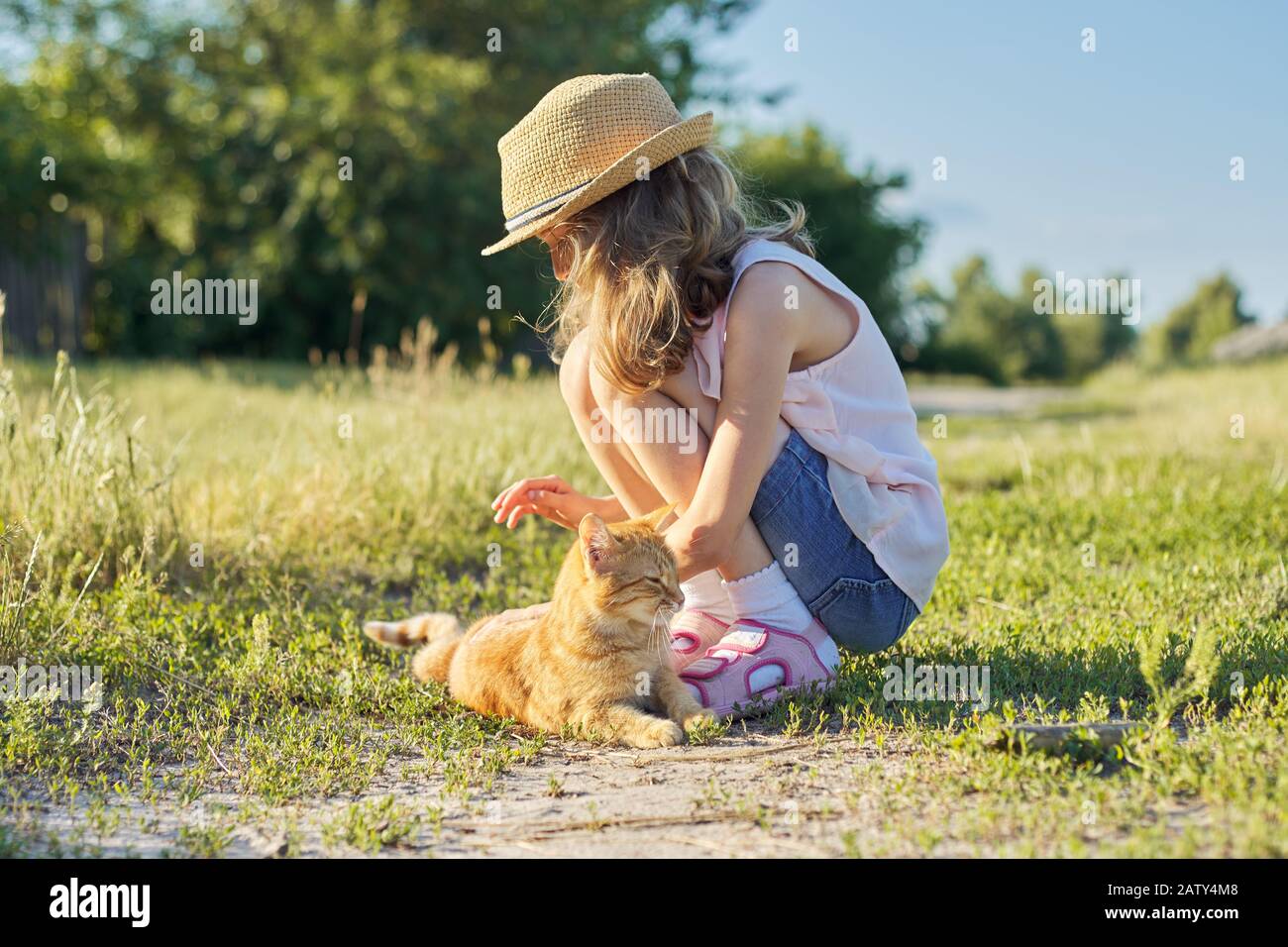 Girl child in hat on country road plays 