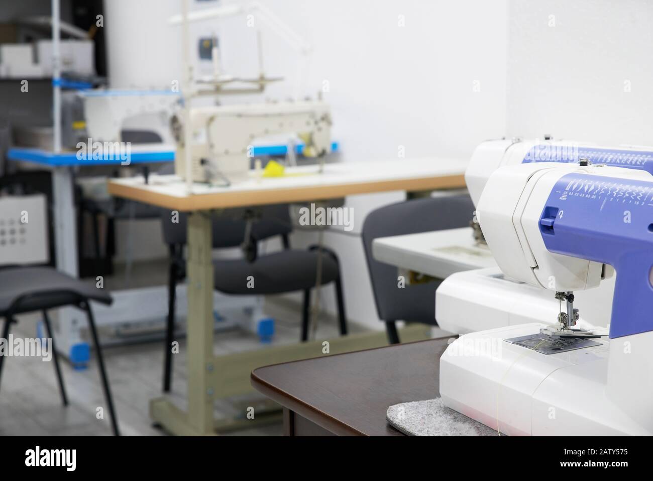 Row of sewing machines in empty atelier studio or tailor shop Stock Photo