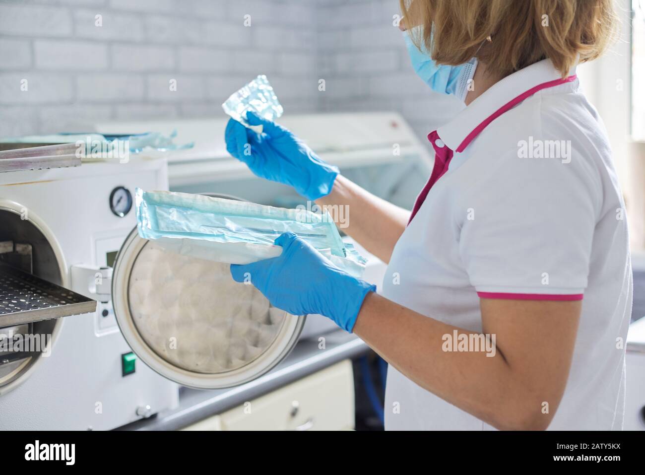 Female nurse doing sterilization of dental medical instruments in