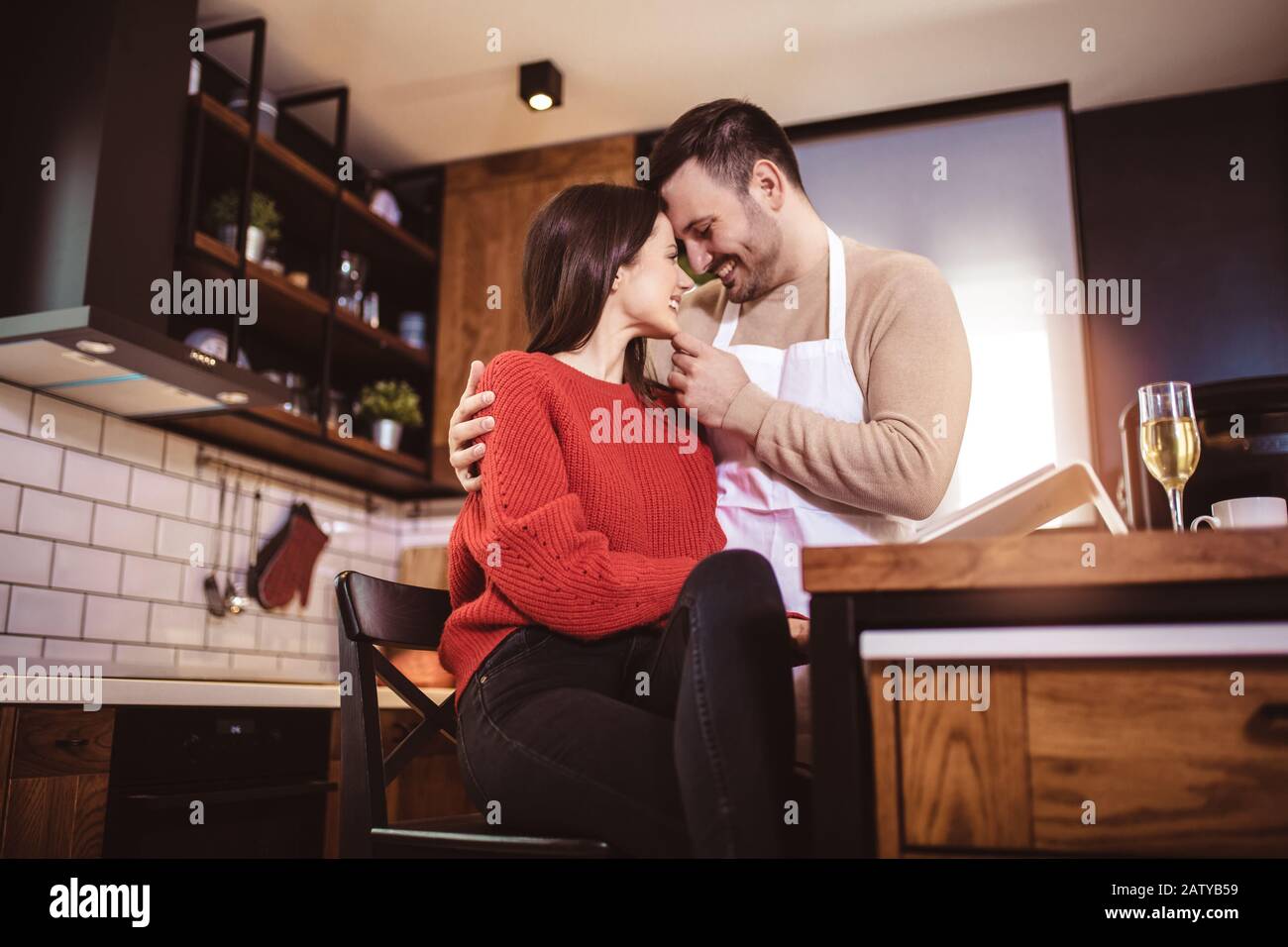 Beautiful couple are hugging and smiling while spending time in kitchen ...