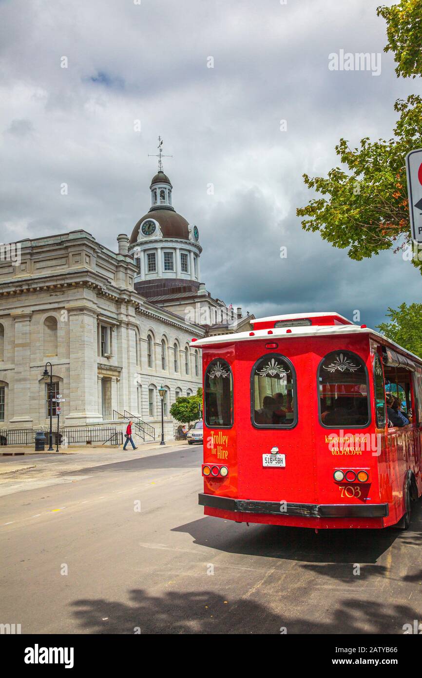 Brock street, Kingston, Ontario, Canada, Aug 2014 - Red trolley bus for hire in front of the city hall building Stock Photo