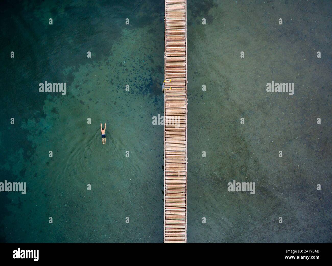 A man swim near jetty in the middle of the lake. The picture taken in Matano lake in South Sulawesi, Indonesia. Stock Photo