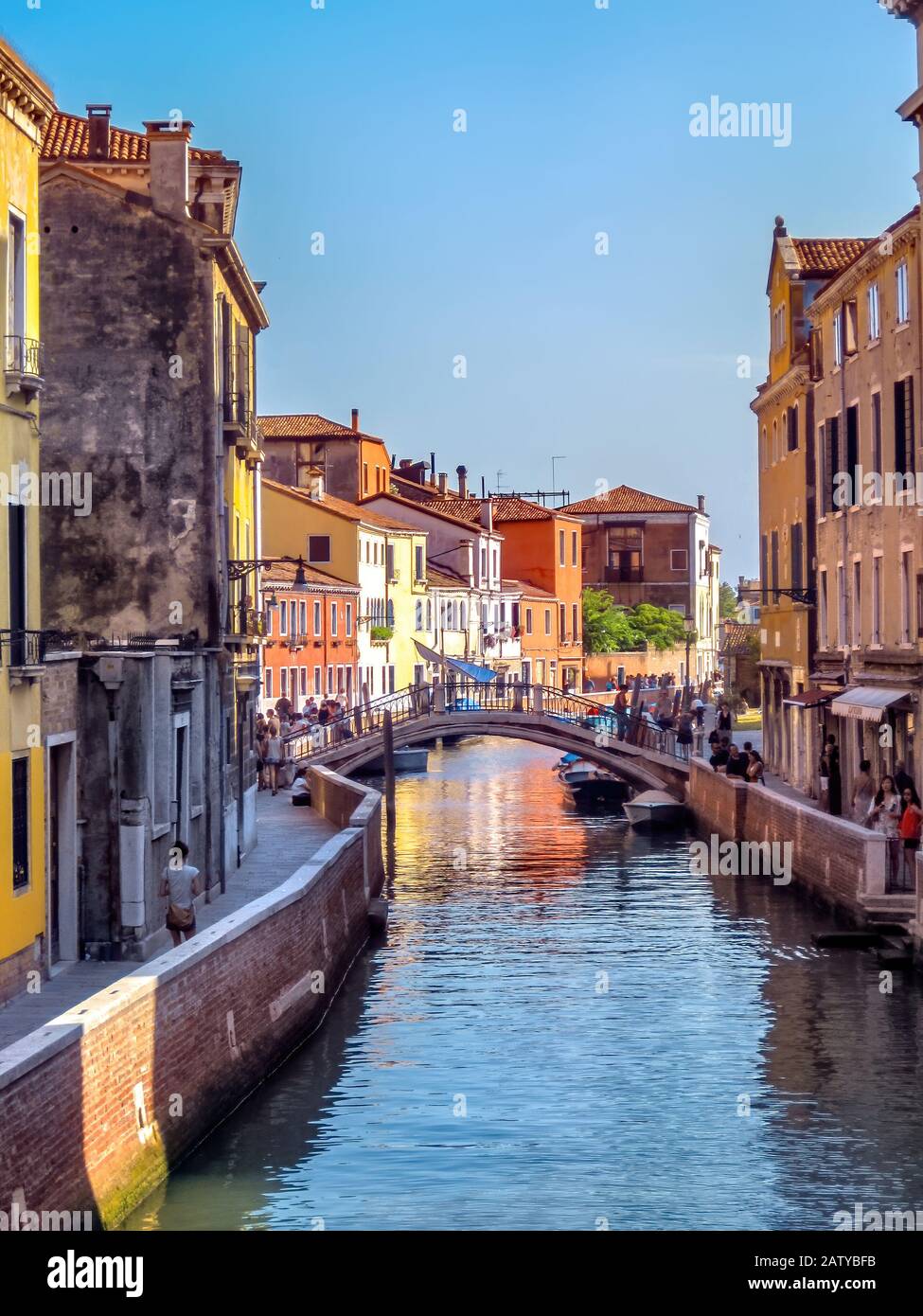 Bridge over a small canal in Venice with the evening sun reflecting in the water, Venice, Italy Stock Photo