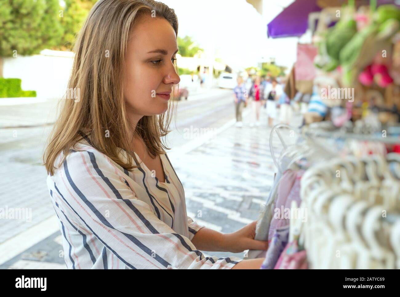 Pretty woman choosing shawl in street shop on vacation. Stock Photo