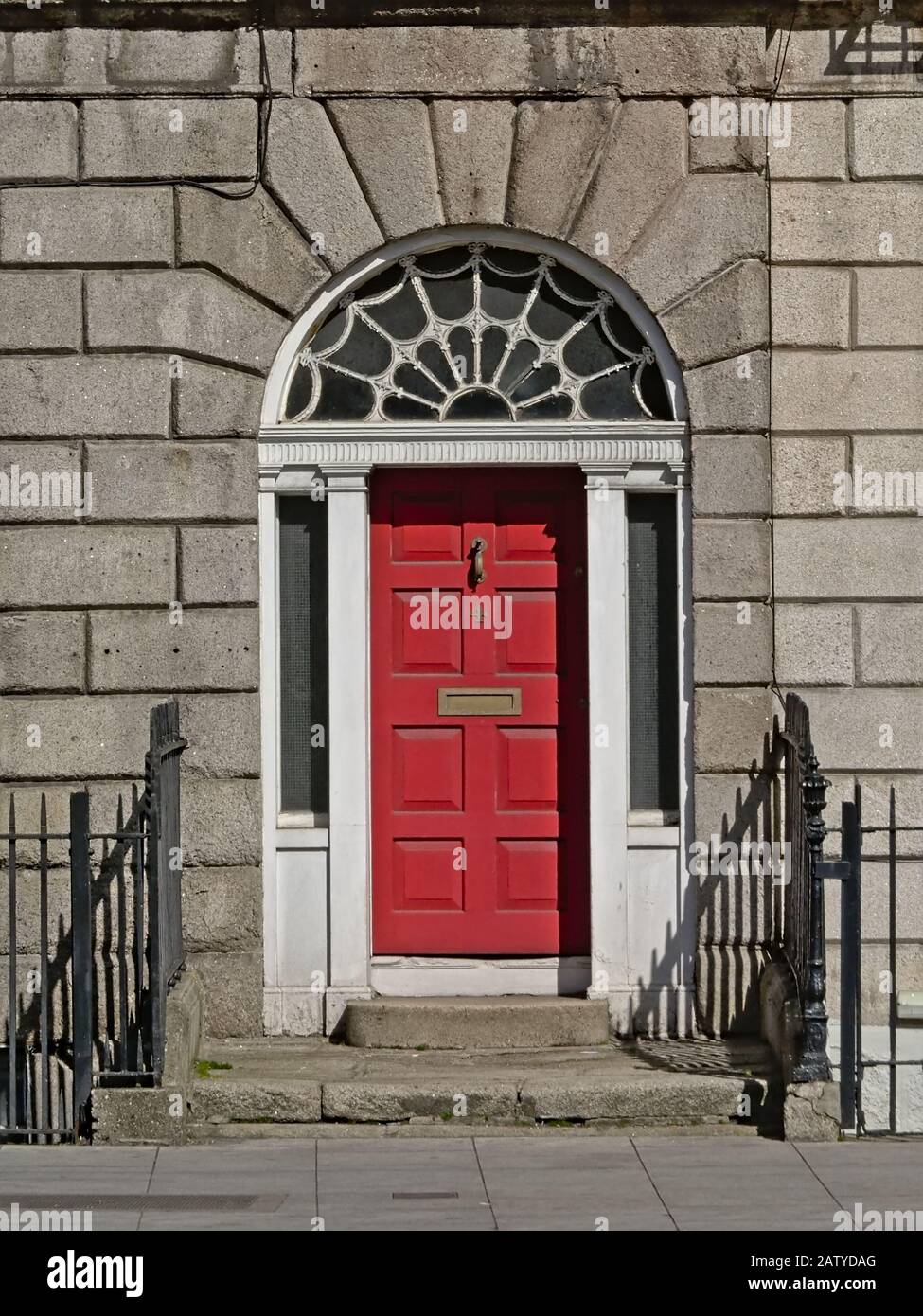 Typical Dublin door painted in red with arch decoration and letterbox