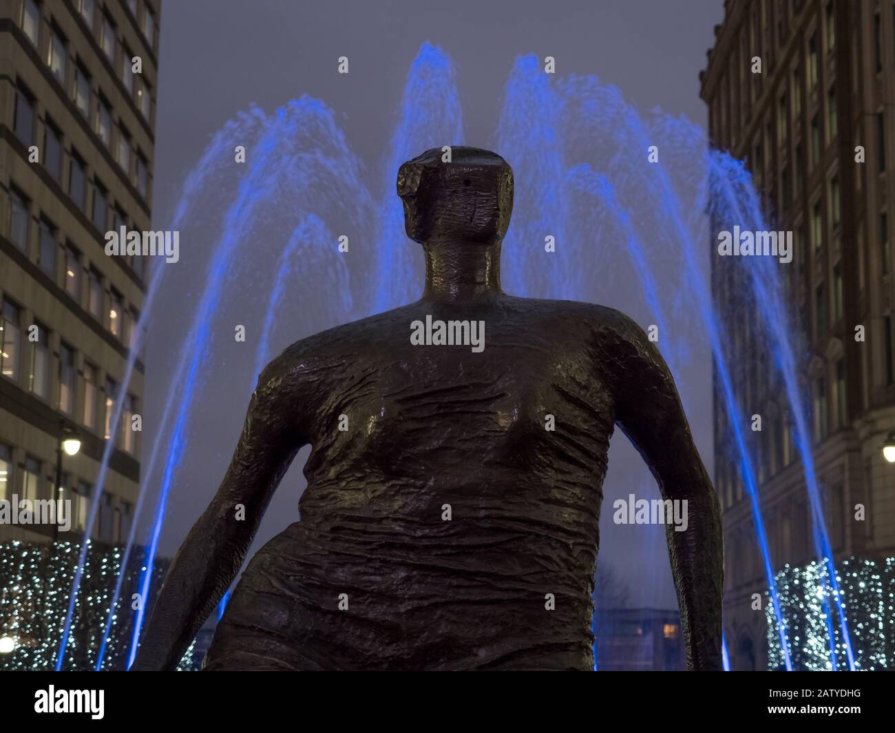 Henry Moor's Draped Seated Woman head and shoulders with blue foundtain light in Canary Wharf during Winter Lights 2020 in the dark at night Stock Photo