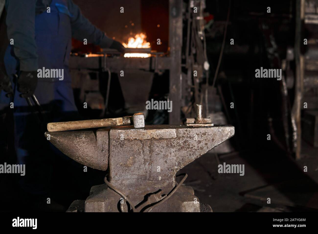 the hammer lies on the anvil in a traditional forge while the blacksmith went to the furnace in the background Stock Photo