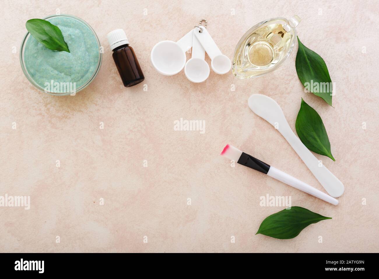 Cosmetology set for cooking, applying face mask. Avocado face mask, spatula, brush, measuring spoons, oil, essential oil on light pink background.Skin Stock Photo