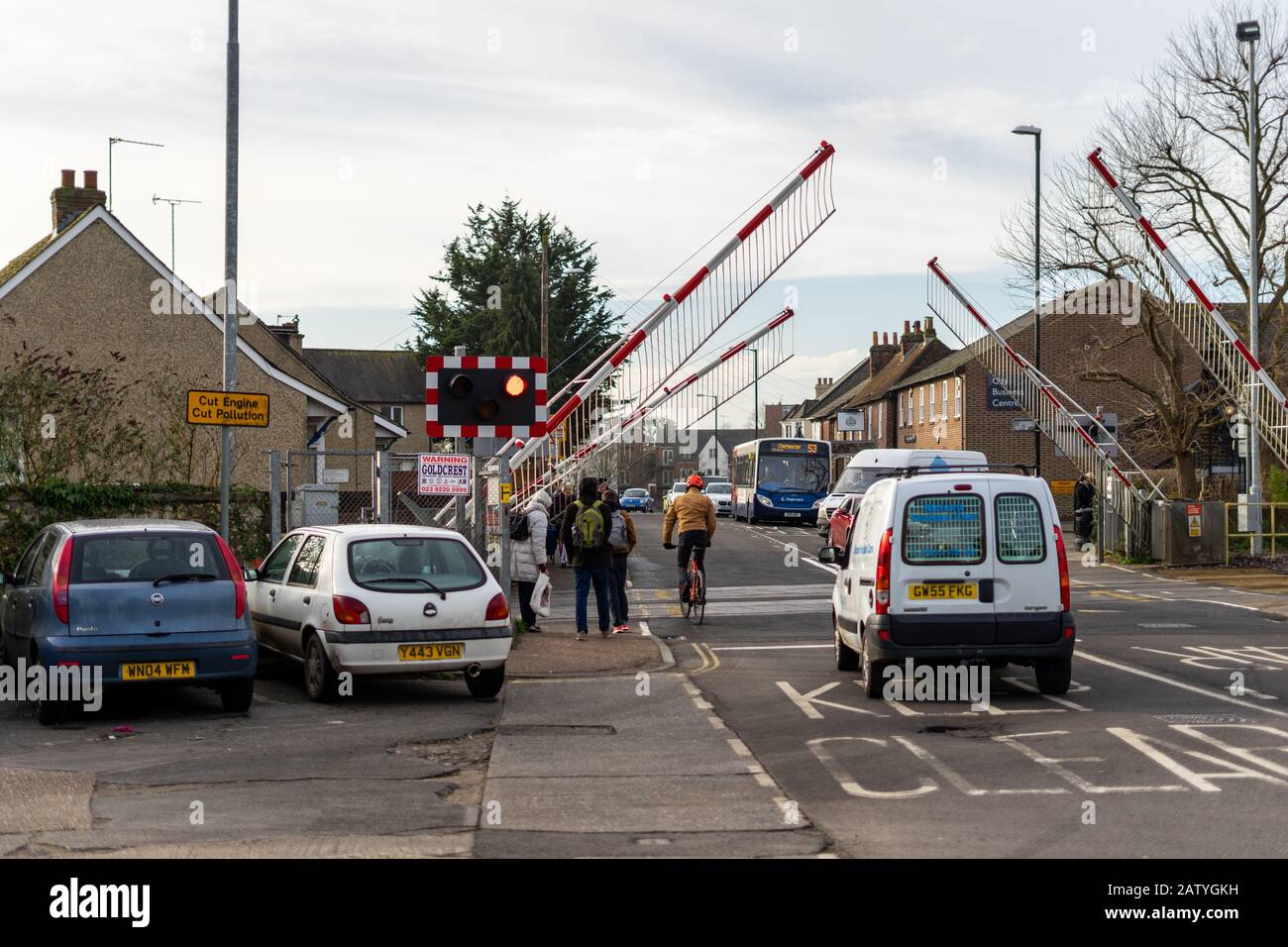 Cars and pedestrians waiting for the railway gates to raise at a level crossing in chichester town centre Stock Photo