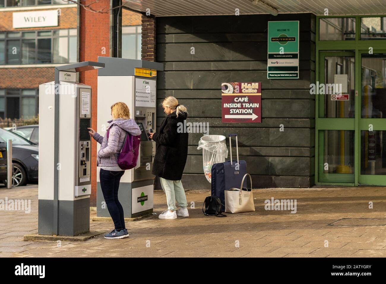 Two young women at a railway station ticket machine buying train ...