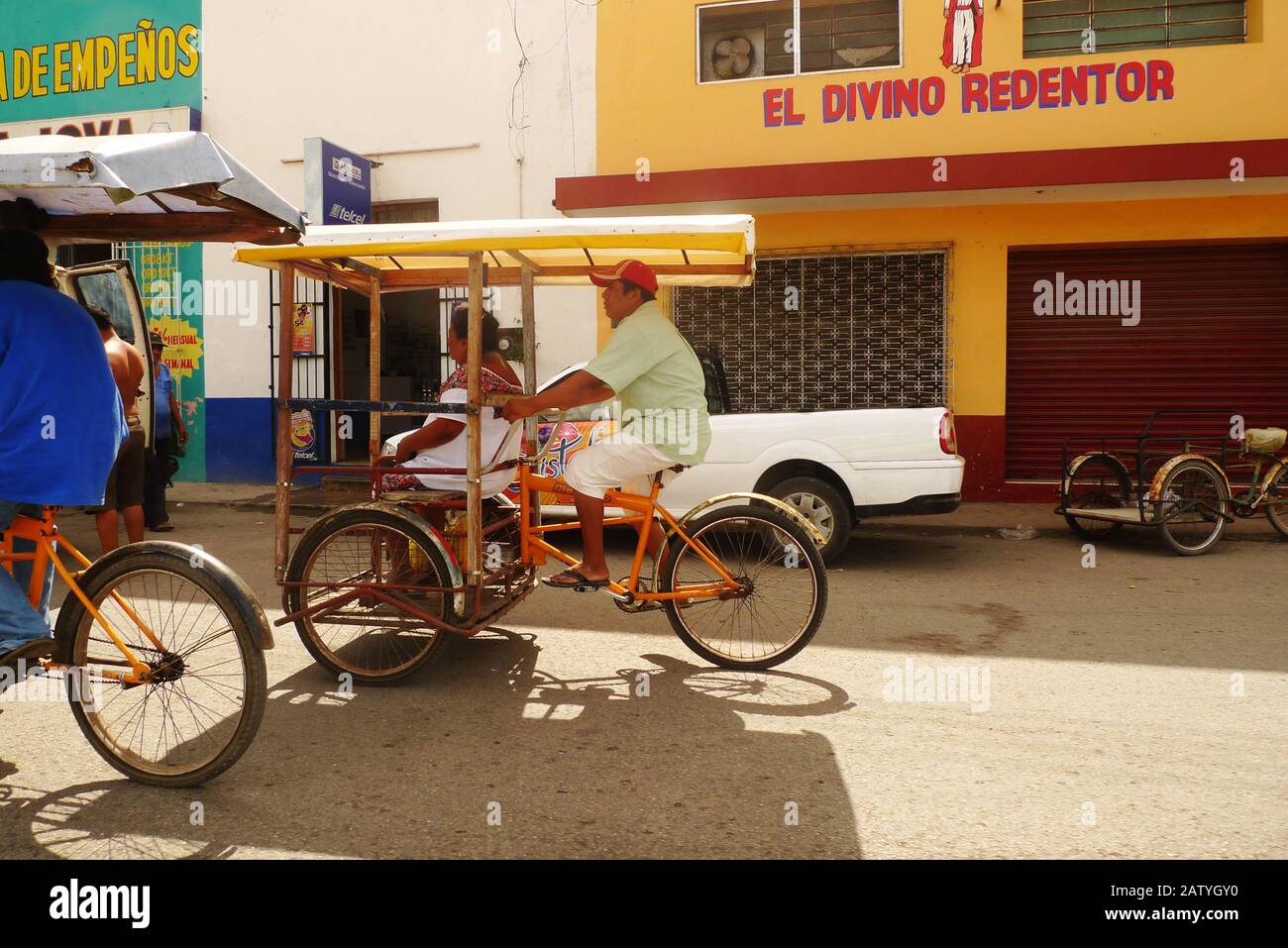 Pedicab (bicycle taxi) on a colonial street in Hunucma, Yucatan, Mexico.  Papel Picado flags fly overhead. Stock Photo