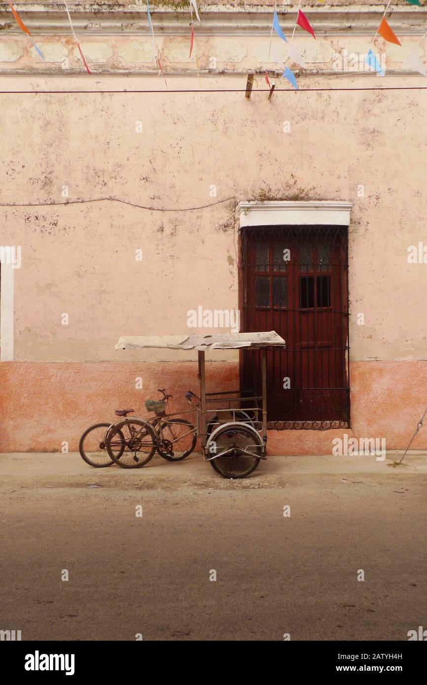 Pedicab (bicycle taxi) on a colonial street in Hunucma, Yucatan, Mexico.  Papel Picado flags fly overhead. Stock Photo