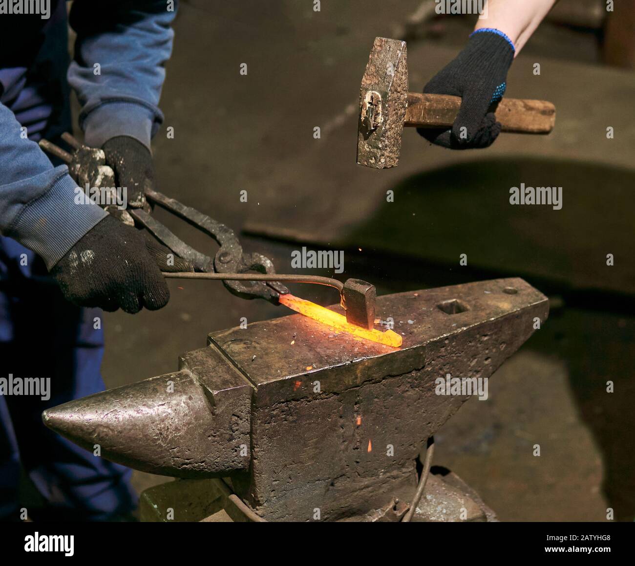 traditional forging of a hot metal billet on the anvil with a hammer and chisel Stock Photo