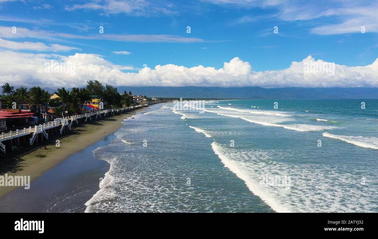 The city of Baler in the Philippines, known as the capital of surfing. Wide  beach with big waves and surfers. Sabang Beach, Baler, Aurora, Philippines.  Summer and travel vacation concept Stock Photo -