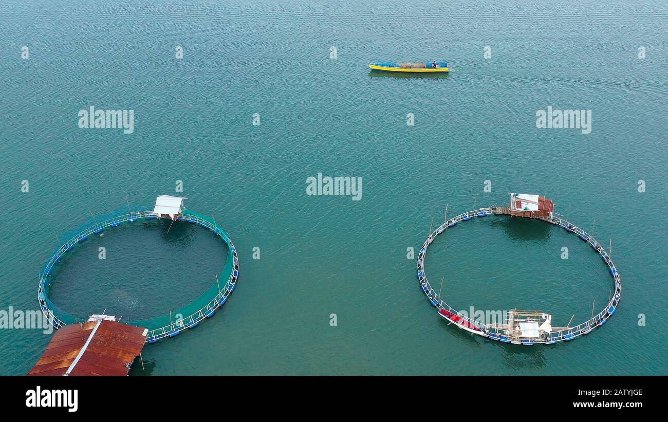 Fish farm with cages for fish and shrimp, top view. Fish cage for tilapia,  milkfish farming aquaculture and pisciculture practices. Philippines,  Luzon. Aerial view of fish ponds for bangus, milkfish Stock Photo 