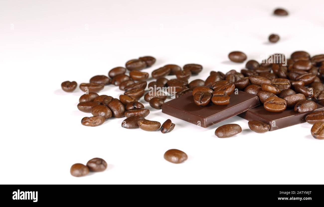 coffee beans on a white background with pieces of black chocolate Stock Photo