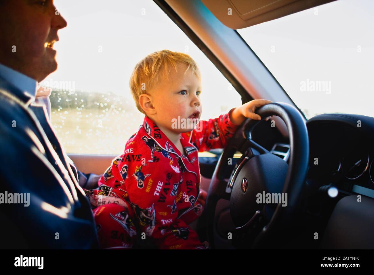 Little boy sitting on his Dad s lap in car driver s seat Stock Photo Alamy