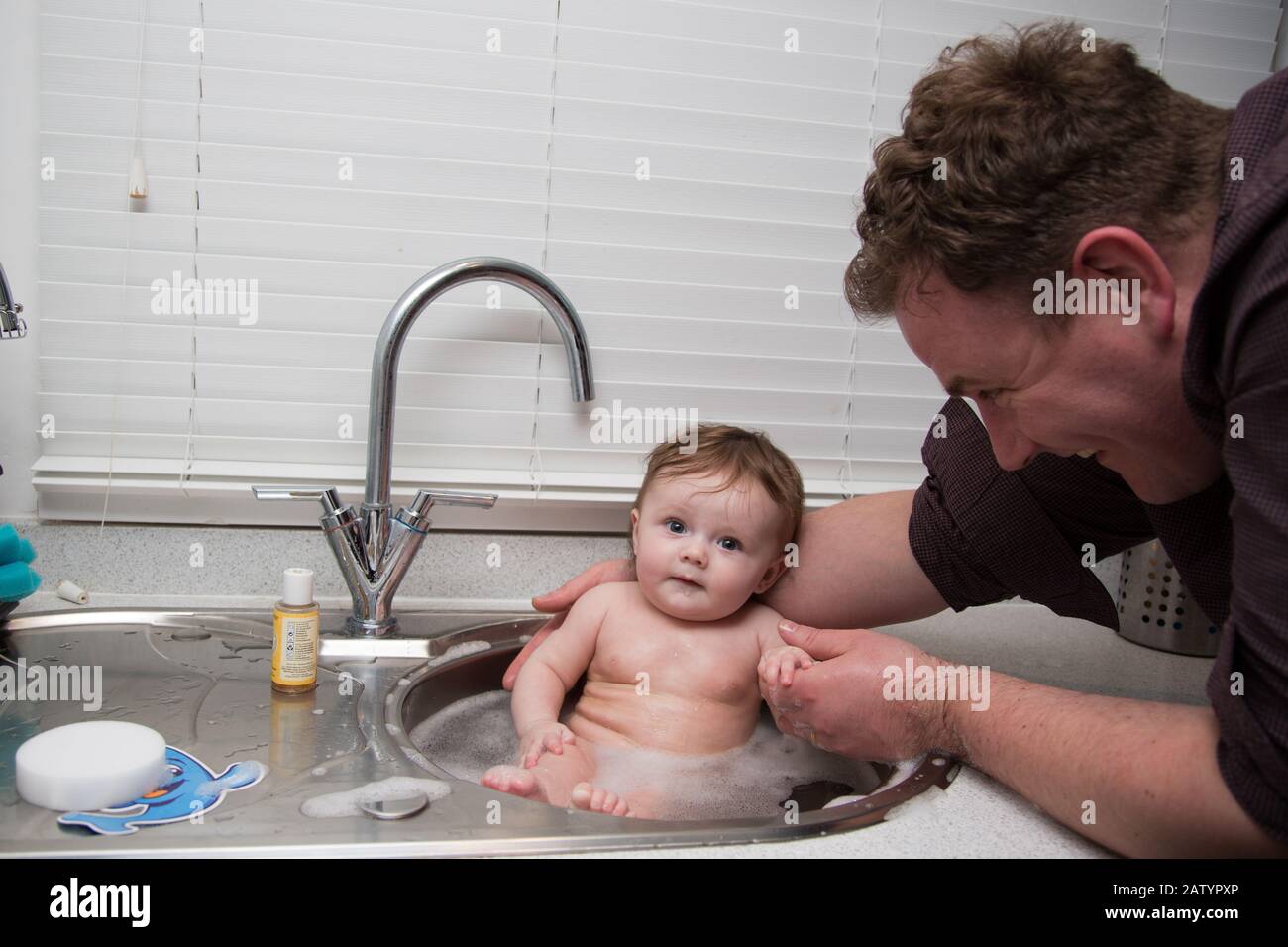 Father bathing his daughter in the kitchen sink, UK Stock Photo Alamy