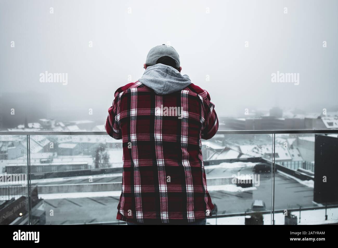 Man on a roof overlooking city in foggy weather Stock Photo