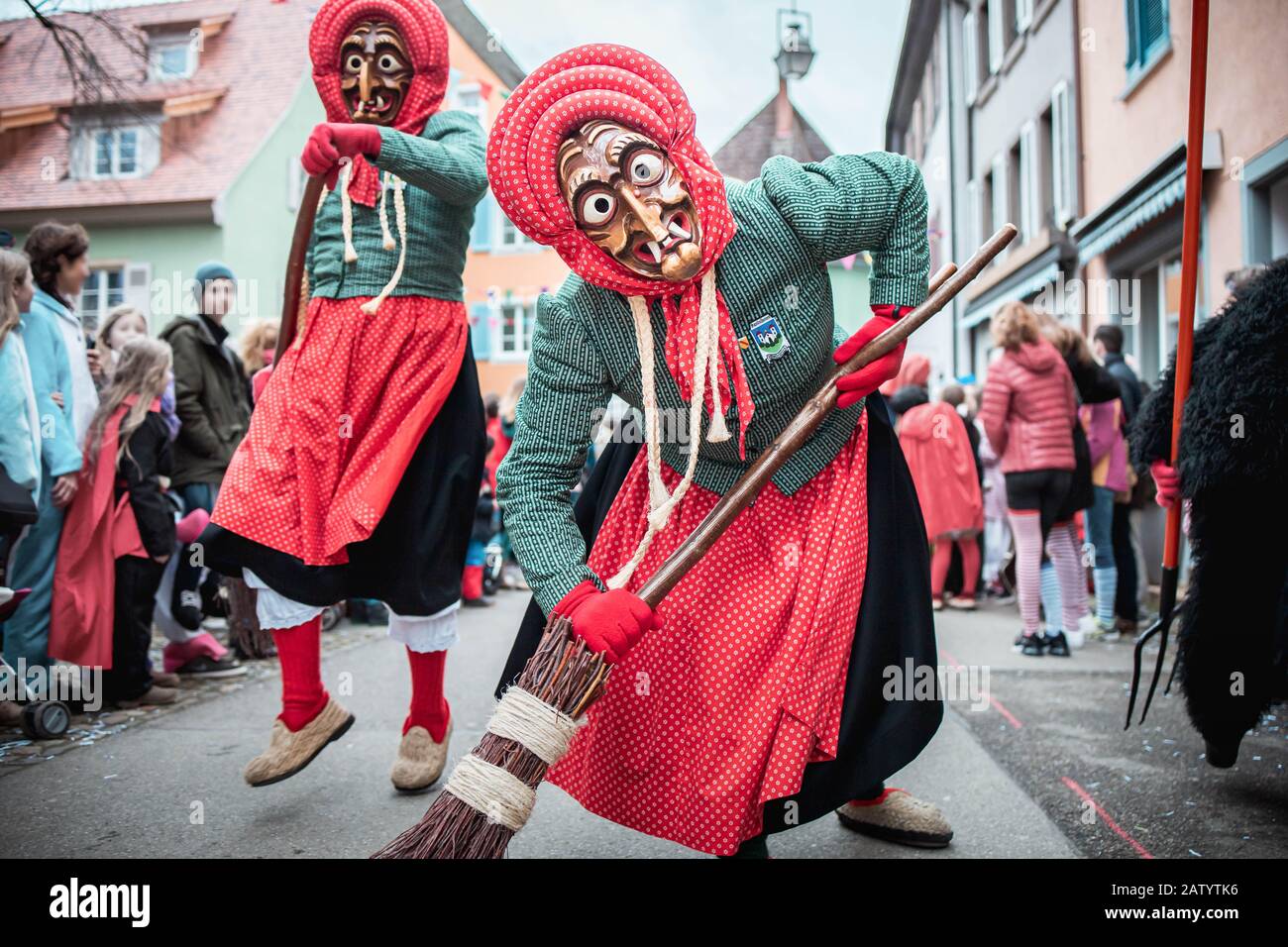 Kandel witch from Waldkirch, beautiful witch in blue and red slowly approaches and leans on the broom. During the carnival parade in Staufen, southern Stock Photo