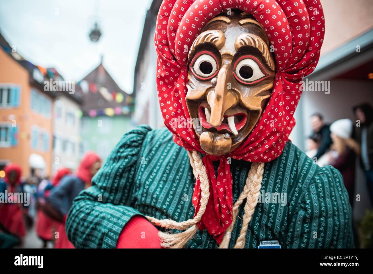 Kandel witch from Waldkirch, beautiful witch in blue-red looks very surprised at the camera during the carnival parade in Staufen, southern Germany. Stock Photo