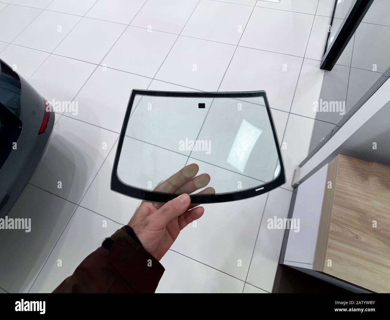 POV of Man hand holding miniature glass windshield inside car auto repair  shop center Stock Photo - Alamy