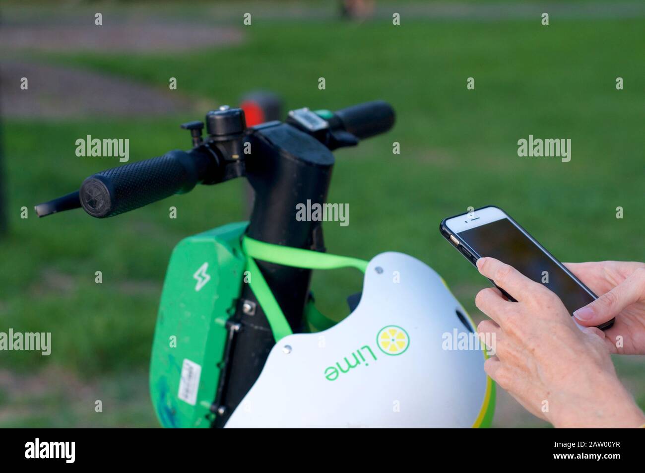 Brisbane, Queensland, Australia - 28th January 2020 : Close up of handlebars and scan symbol of a lime-S electric scooter and hand holding mobile phon Stock Photo