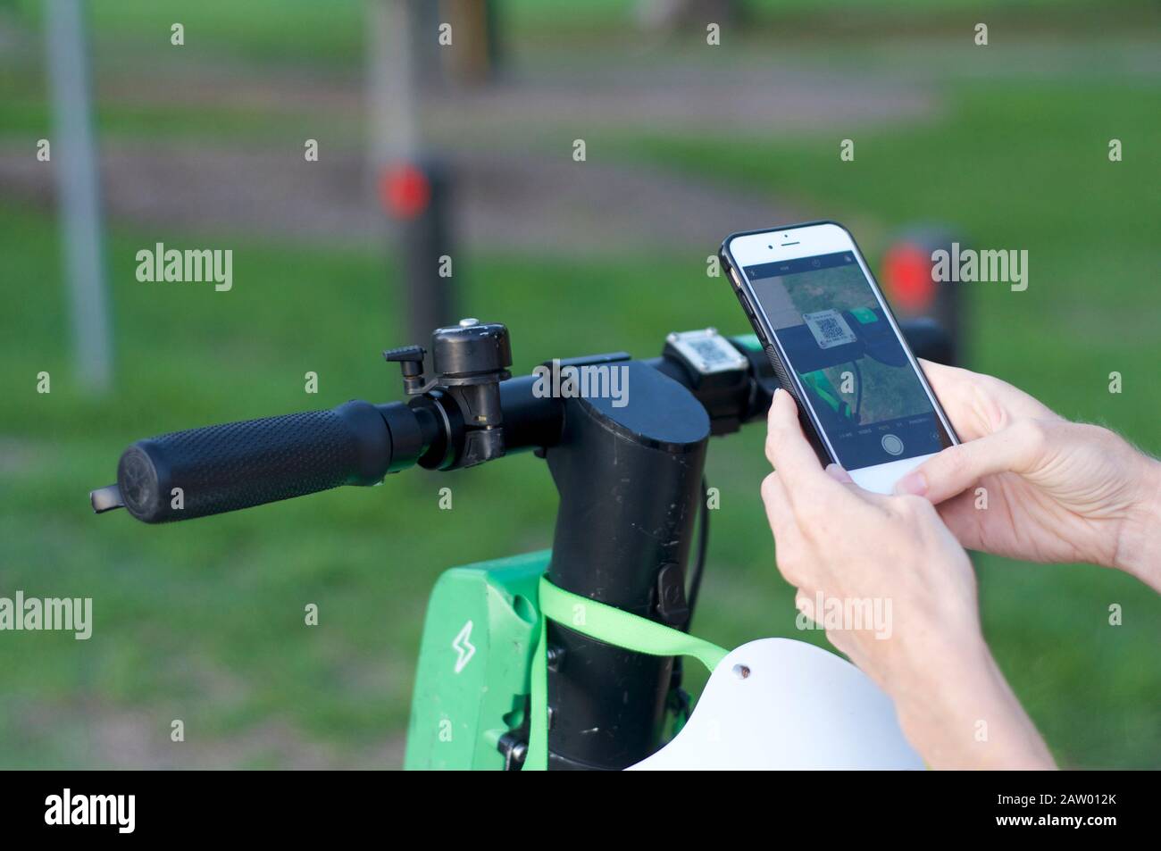 Brisbane, Queensland, Australia - 28th January 2020 : Close up of handlebars and scan symbol of a lime-S electric scooter and hand holding mobile phon Stock Photo