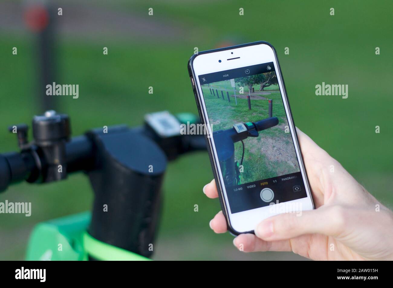 Brisbane, Queensland, Australia - 28th January 2020 : Close up of handlebars and scan symbol of a lime-S electric scooter and hand holding mobile phon Stock Photo