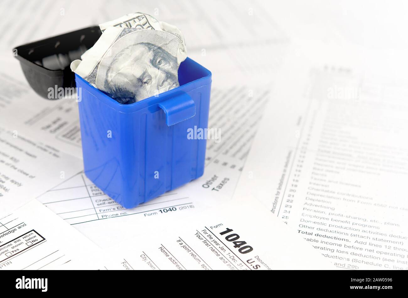 Many american tax blank forms and crumpled hundred dollar bill in trash