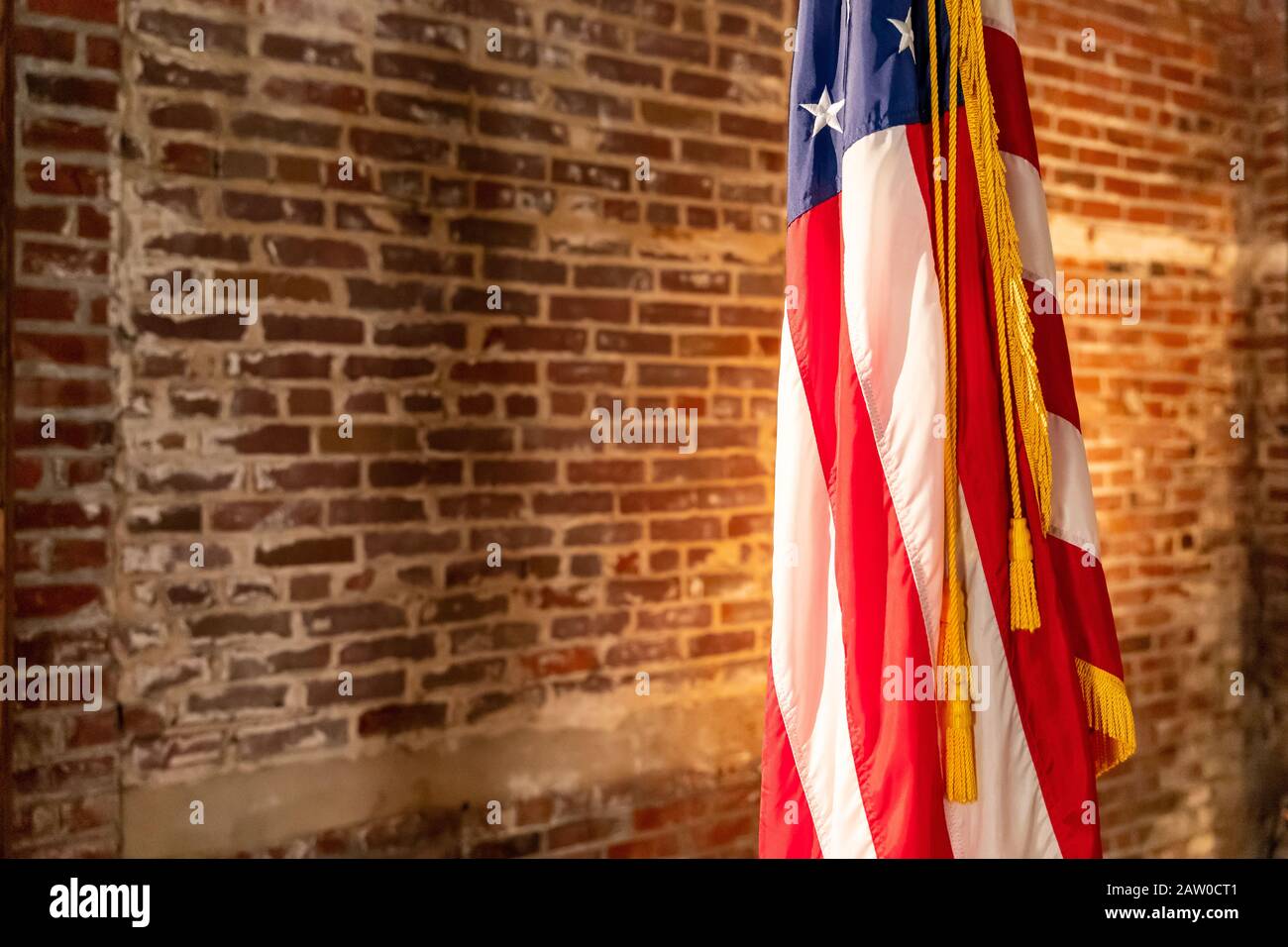 American Flag on Stand, against old brick wall, with copy space. Stock Photo
