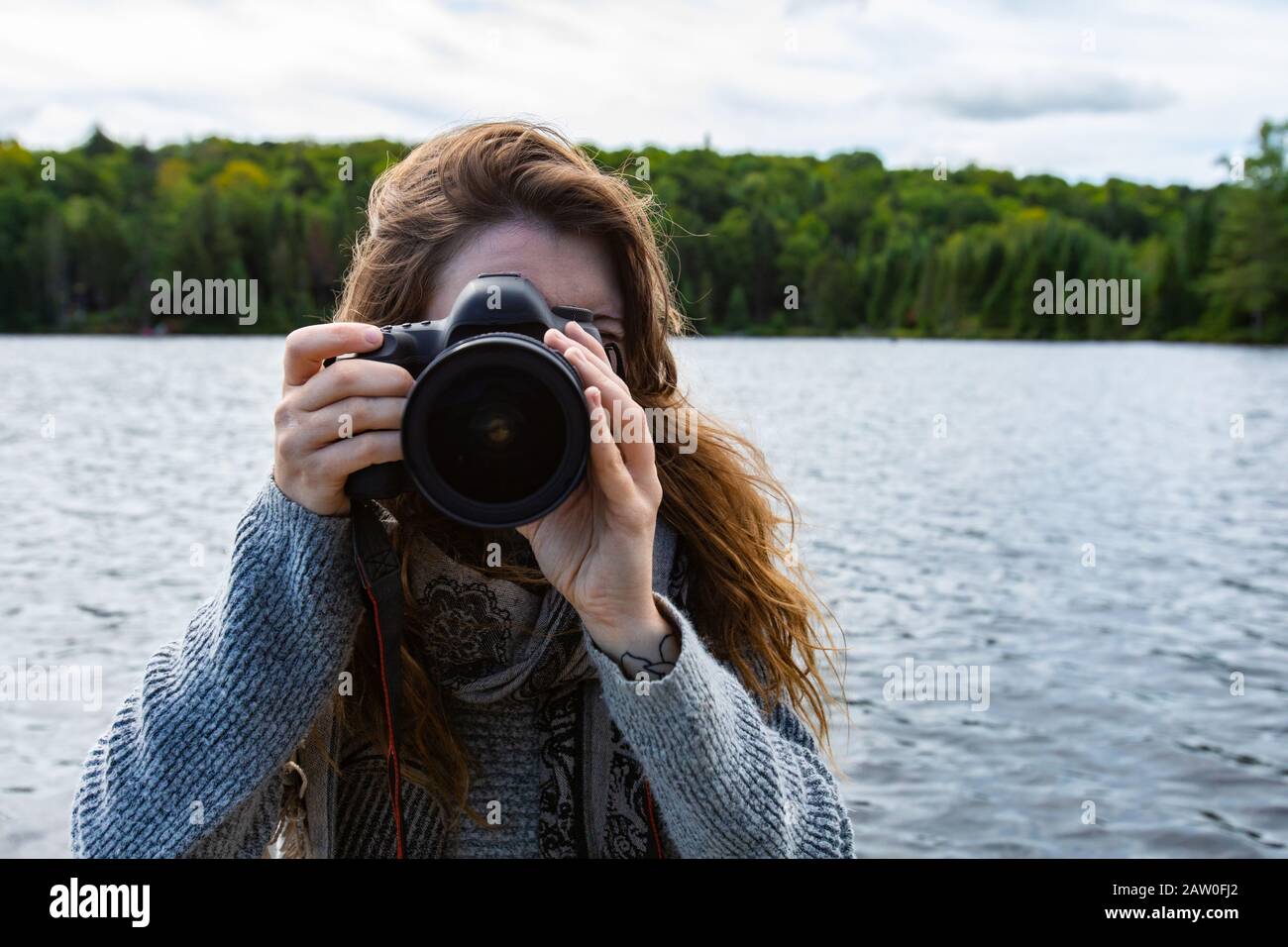 Young woman traveler clicking pictures using DSLR camera while in lake of  Northern Quebec in Canada with fur and spruce tress in background Stock  Photo - Alamy