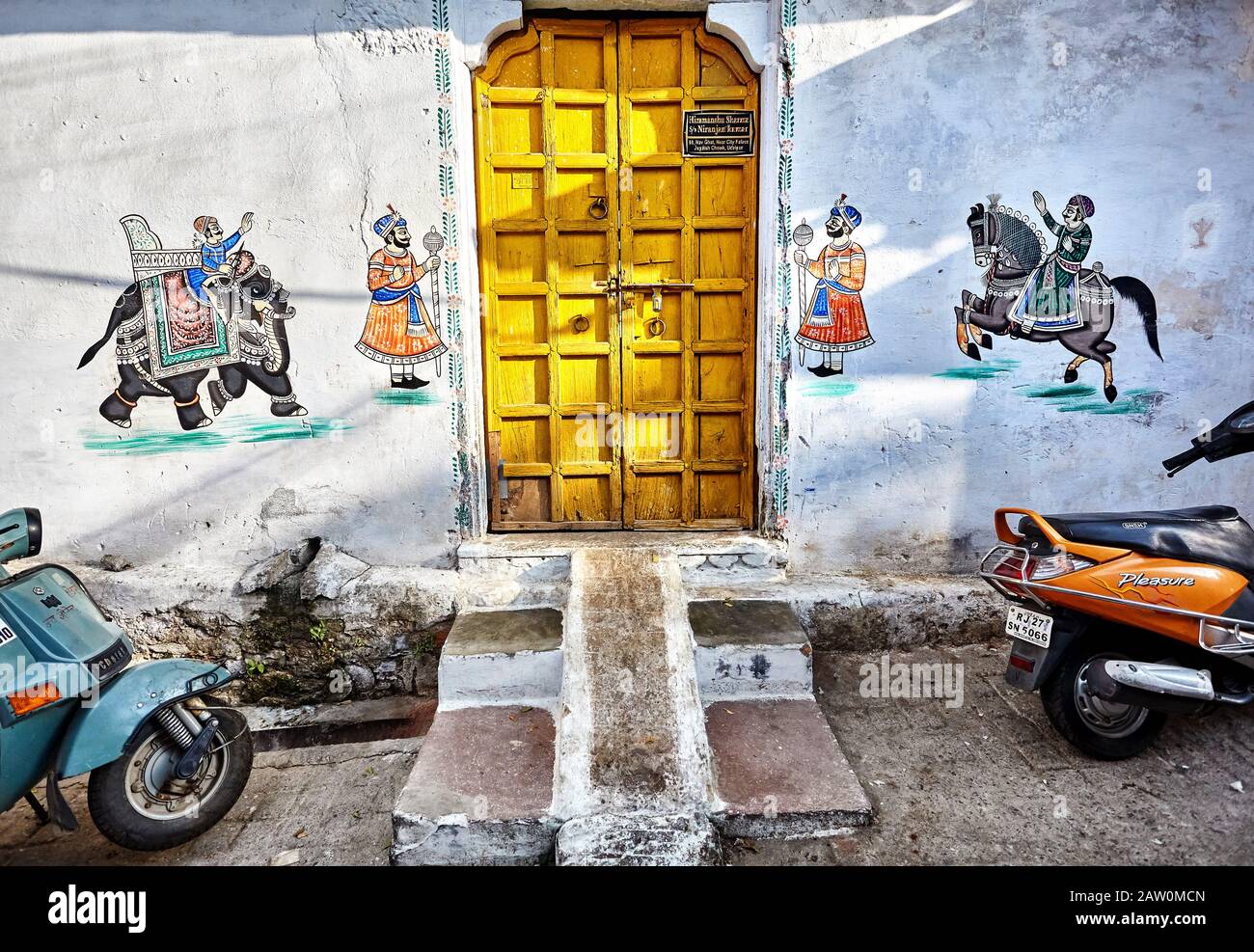 UDAIPUR, RAJASTHAN, INDIA - MARCH 03, 2015: Beautiful Paintings of Maharajas on elephant and horse at wall of house with yellow door in Udaipur city. Stock Photo