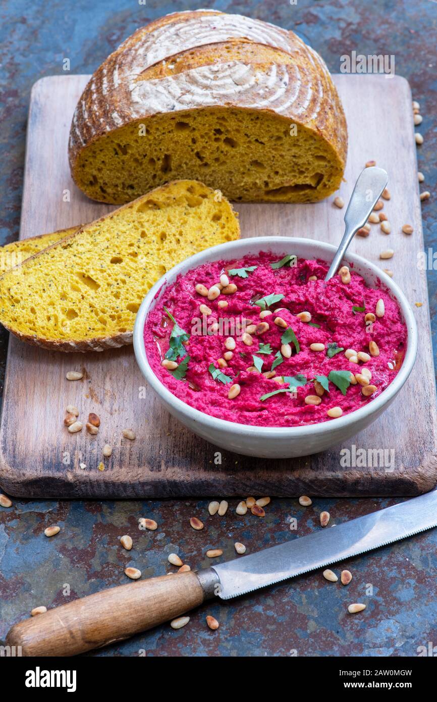 Homemade roasted beetroot hummus and turmeric sourdough bread on a slate background Stock Photo