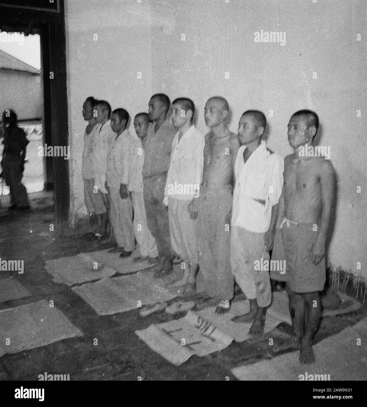 [nine captured Japanese? are in a row] [there are mats on the floor ...