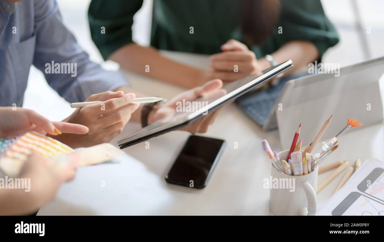 Close up view of application developer team using digital tablet while consulting on their UI project in simple co working space Stock Photo