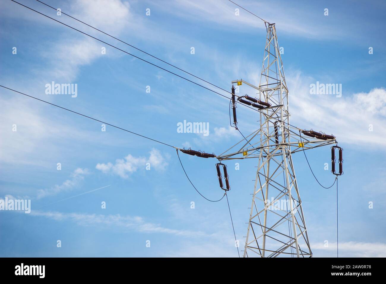 High voltage electric pole with wires on blue sky background. Line of electricity transmissions and distribution Stock Photo
