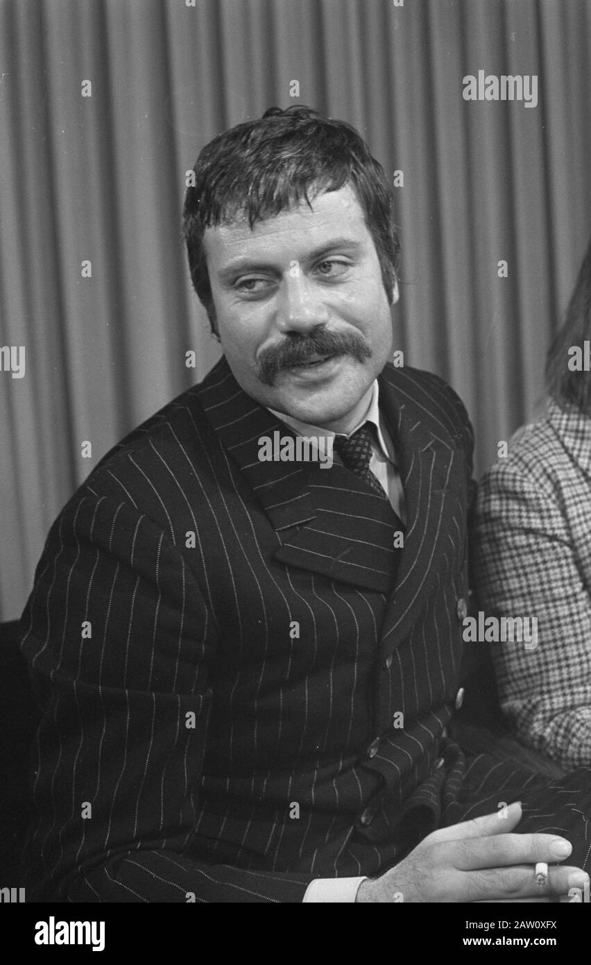 Oliver Reed hands clasped wearing costume as he appears in film