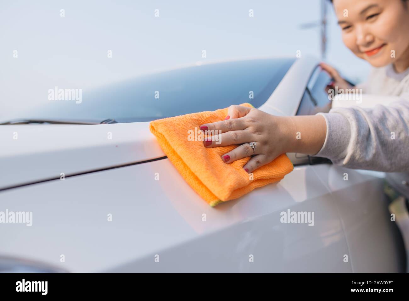 Hand wiping the windshield of a car on a sunny day. Wipe dry with an orange  sponge. Rag wipes water stains on the window Stock Photo - Alamy