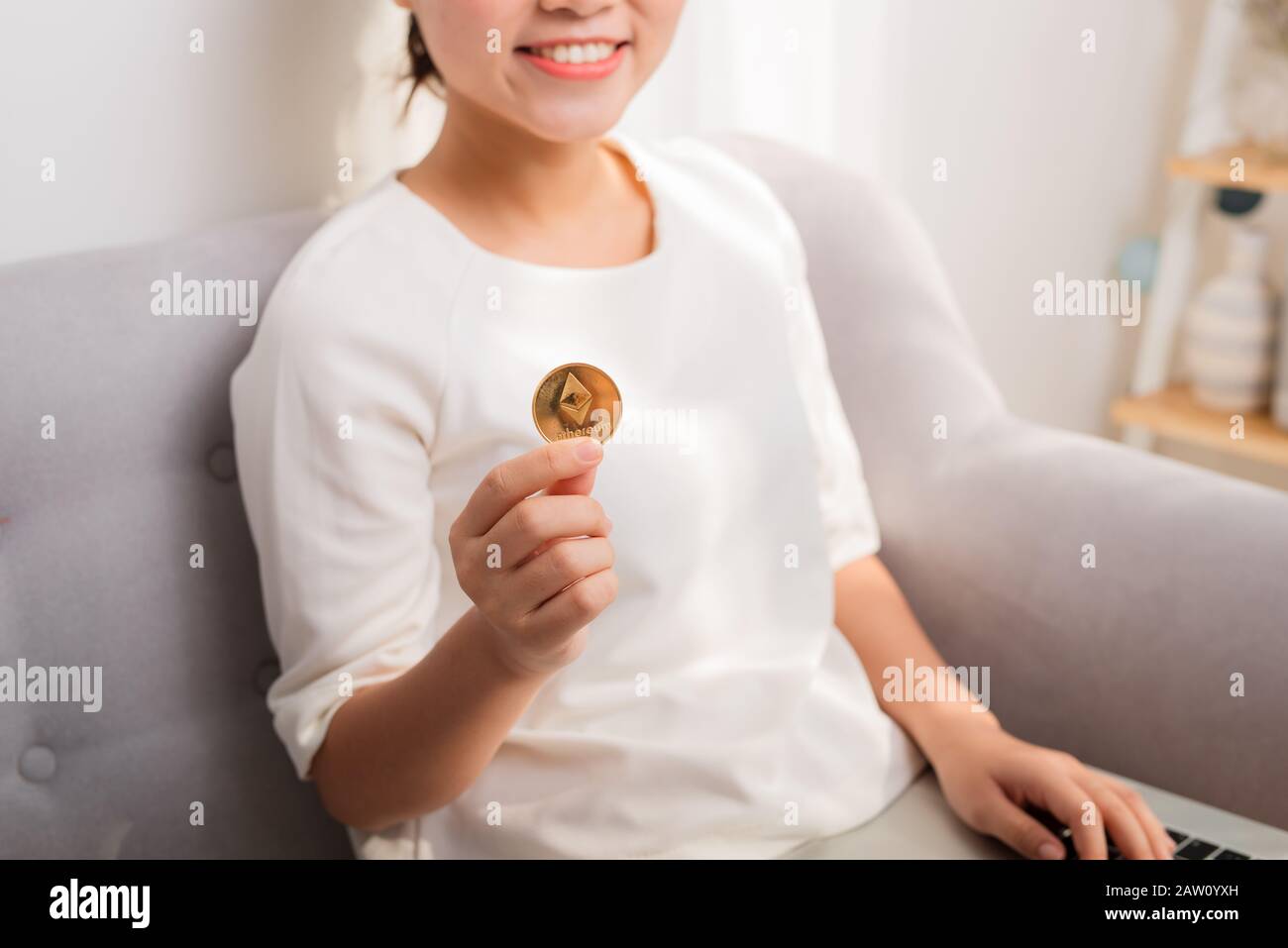 Asian woman gets big money! Attractive woman with holds bitcoin in hands and looks into the camera. Stock Photo