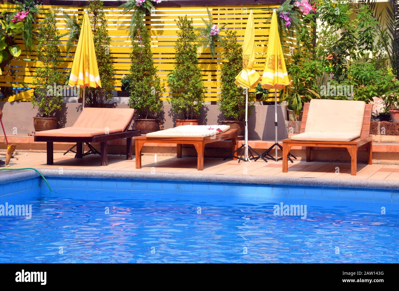 Empty sunloungers beside a swimming pool Stock Photo