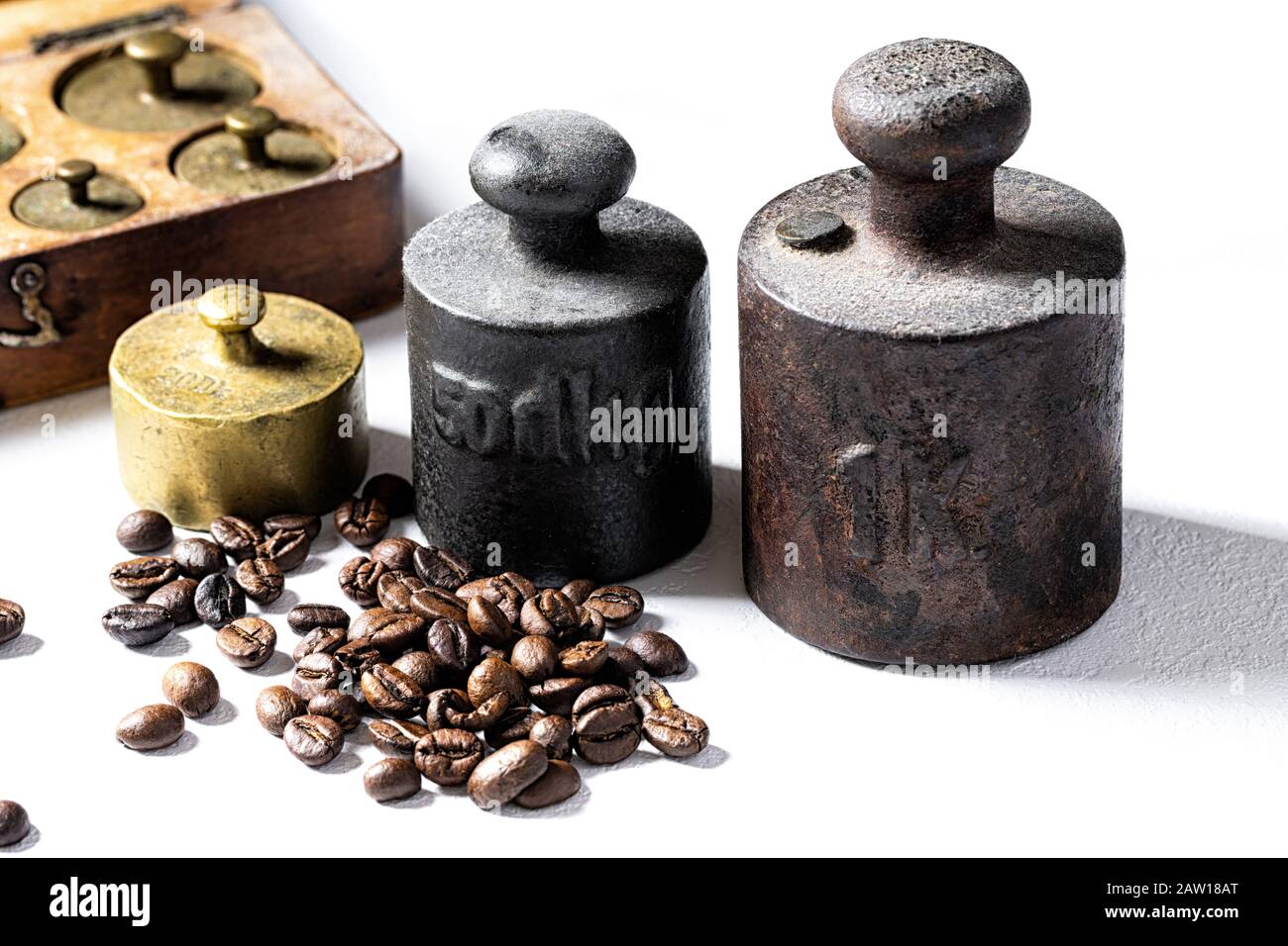 Old rustic metal weights with coffee beans on white background. Stock Photo