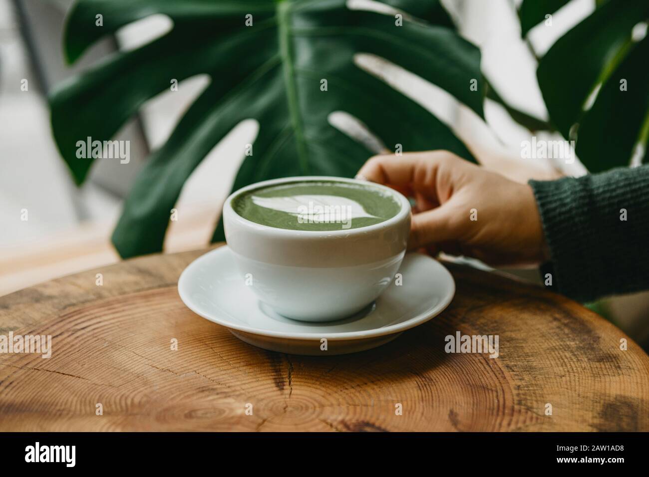 Girl drinks aromatic fresh and healthy green matcha latte tea in a cafe. Stock Photo