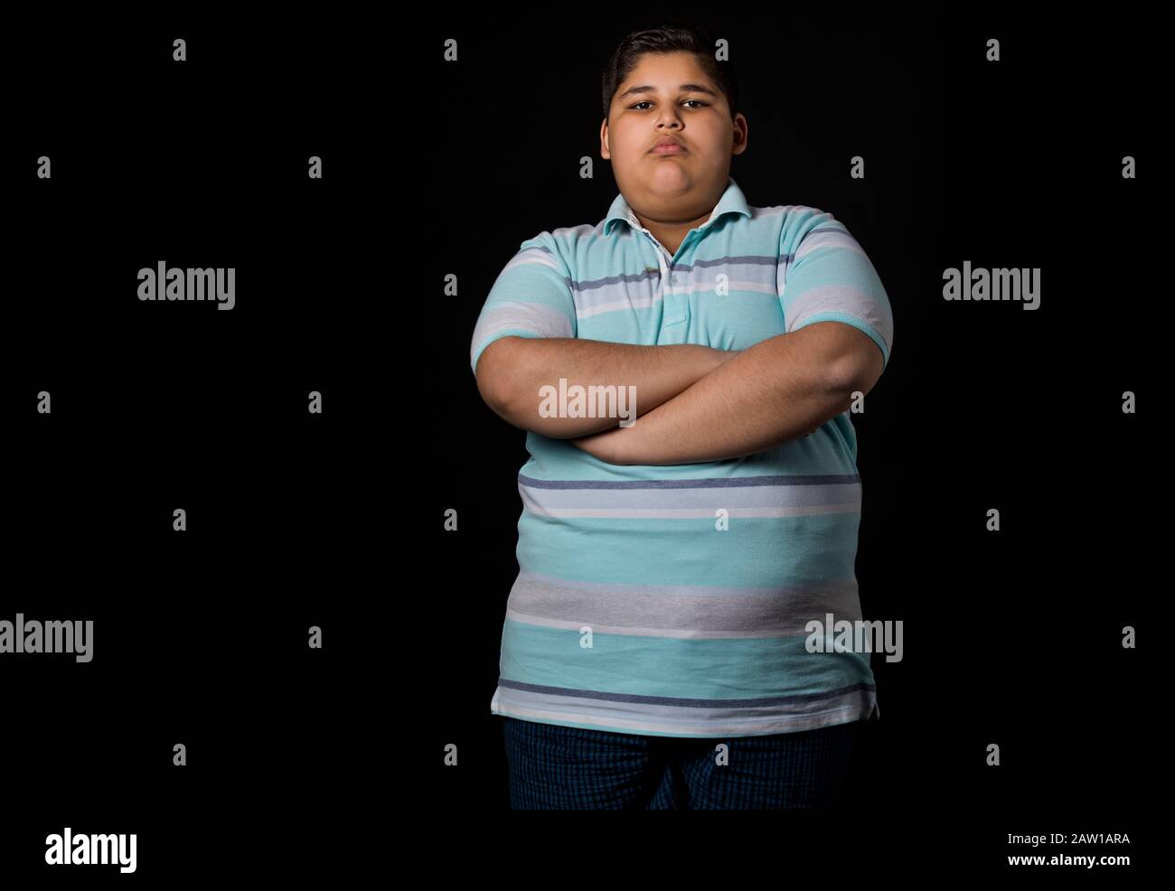 Young boy standing with his hands folded on his chest. (Obesity) Stock Photo