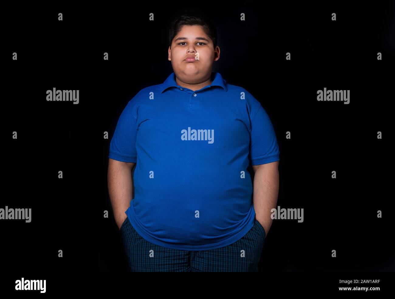 Young boy standing with his hands in his pockets. (Obesity) Stock Photo