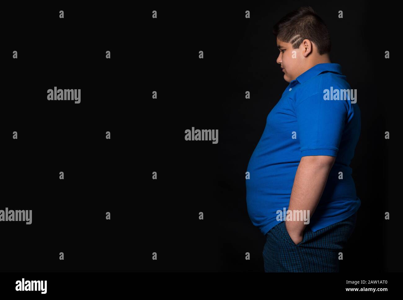 Young boy standing sideways with his hands in his pockets. (Obesity) Stock Photo